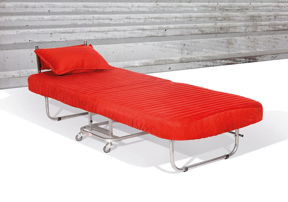 یک مبل تاشو فلزی که در حالت باز یعنی تختخواب قرار دارد این مبل به رنگ قرمز است