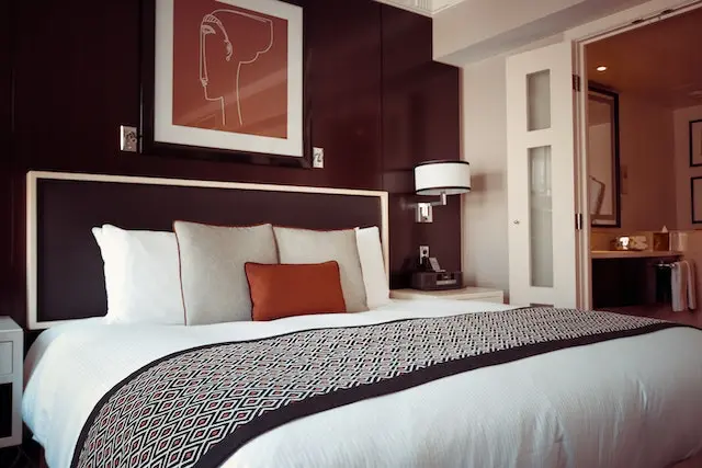 یک تختخواب بزرگ در یک اتاق قرار دارد و مرتب با کوسن ها تزئین شده است