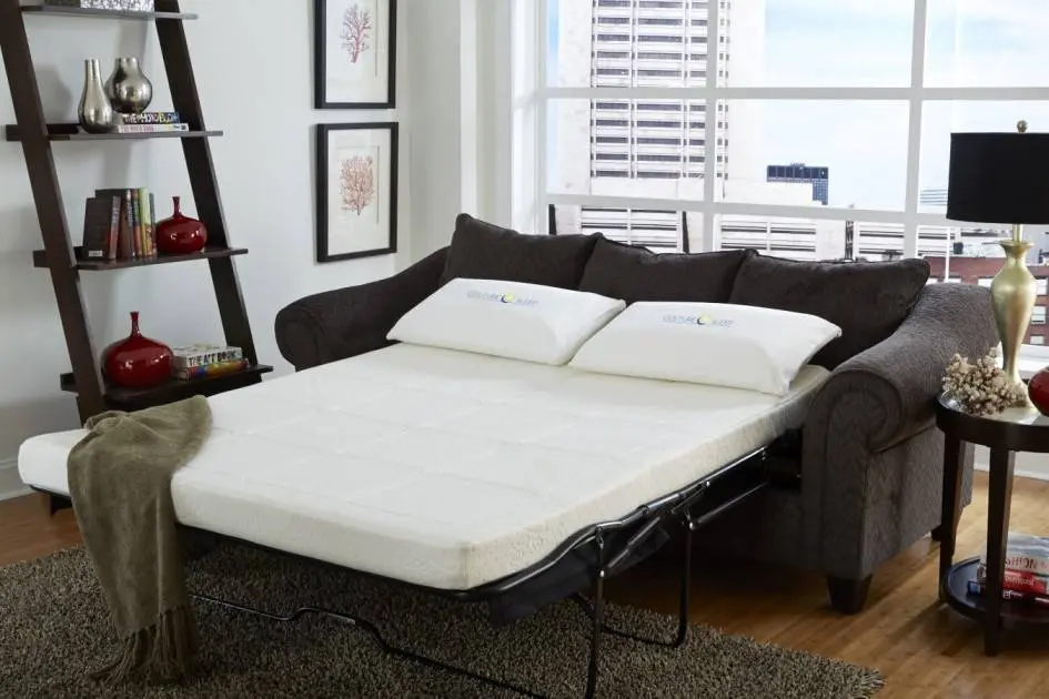 تخت تاشو مشکی با تشک سفید که در پشت آن پنجره قرار دارد و در کنا تخت دکور چوبی قرار دارد