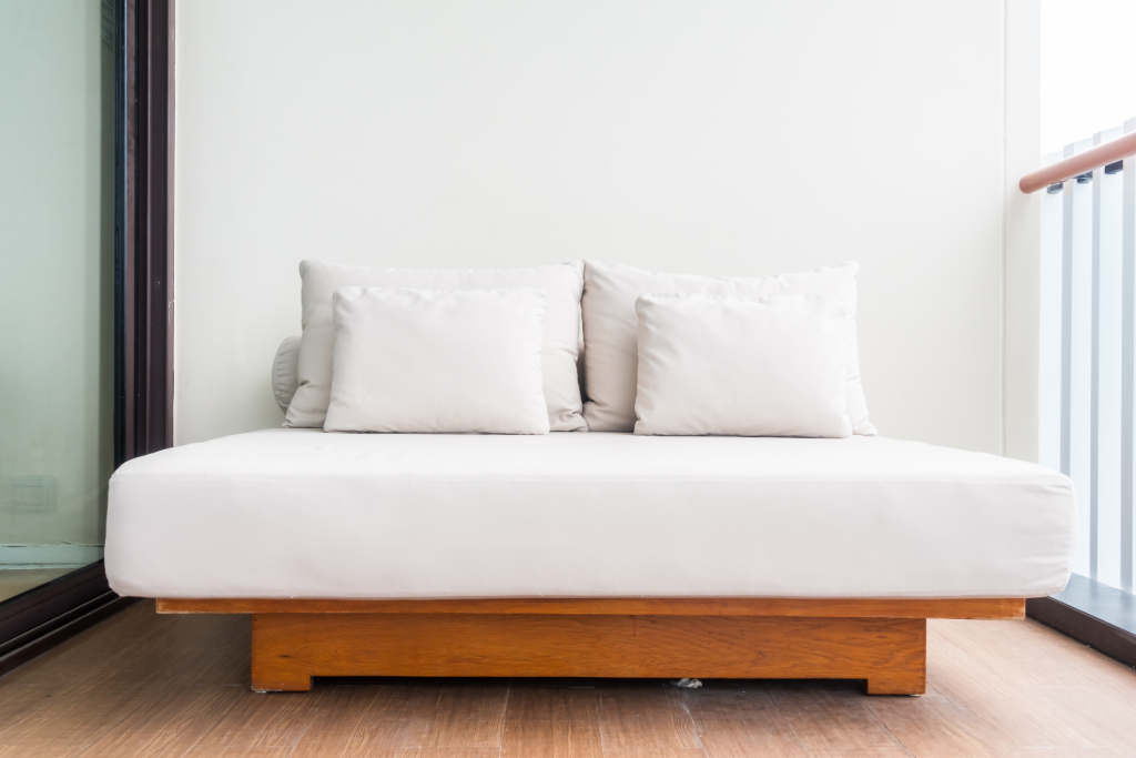 مبل تخت خواب شو سفید که چوب های ان که در زیر قرار دارد قهوه ای میباشد و ۴ عدد بالشت نیز بر روی ان قرار دارد