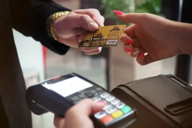دست یک خانم و آقا که در حال رد و بدل کردن کارت اعتباری هستند که برای یک خرید اقساطی نیاز است.